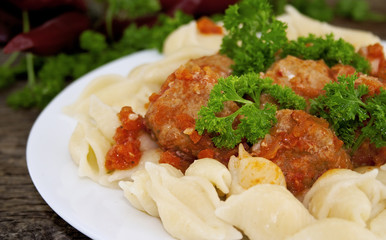 Pasta Conchiglie and meatballs with tomato sauce on rustic woode
