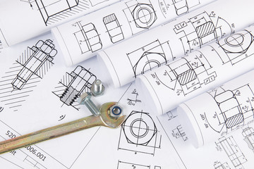 Wrench, bolts and nuts on a background of engineering drawings. Science, mechanics and mechanical...