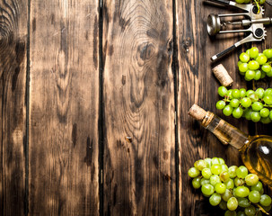 White wine with a corkscrew and branches of grapes.