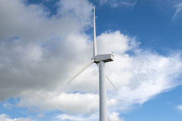 Wind mill against blue sky with clouds for energy production