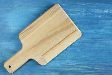 Empty wooden cutting board on rustic blue table, background with space for text, top view.