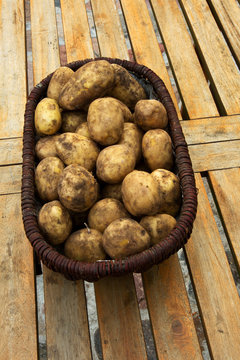 A basket full of potatoes on wooden table