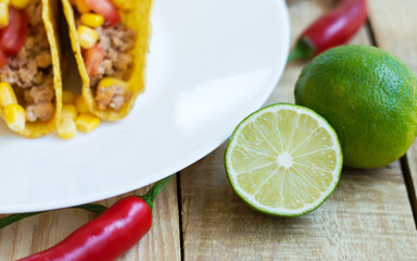 Fresh lime on wooden table, mexican tacos and red chili pepper as background