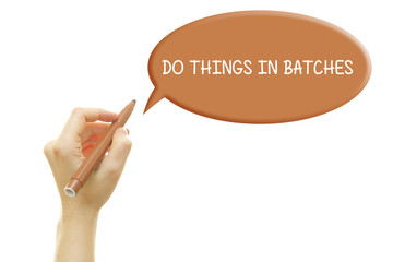 Woman hand writing DO THINGS IN BATCHES with a marker isolated on white.