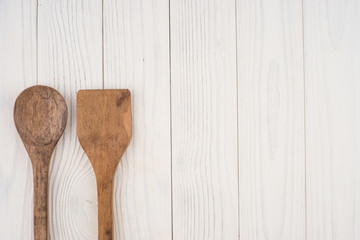 Wooden spoon and spatula on old white table.