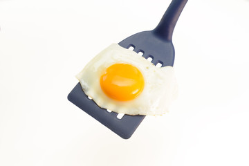 Fried egg on the spatula, ready to be served. White background.