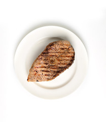 Grilled steak of fish in a plate on a white background