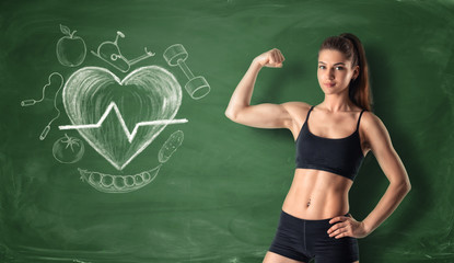 Fitness girl showing her bicep on the background of a chalkboard with drawn beating heart and sport...