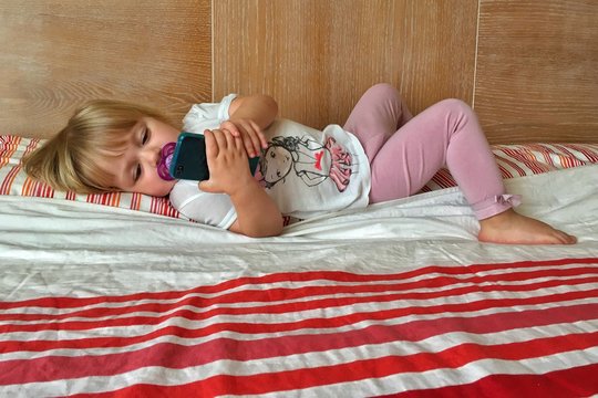 sul letto dei genitori con lo smartphone