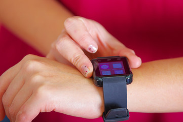 Closeup arm wrist wearing smart watch, screen lit up, using other hand pressing on device, white studio background