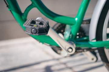 Close up of pedal of green bicycle outdoor.