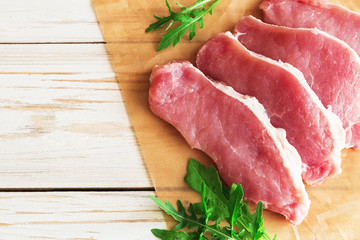Fresh raw pork meat with salt, pepper and arugula.