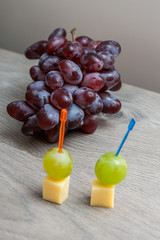 Canape with white grapes and cheese on the background bunch of red .