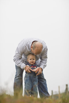 Portrait of a young toddler standing with his father.