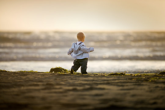 Young toddler walking on the beach.