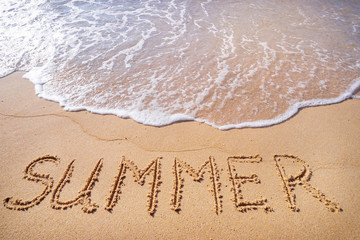 Vacation concept on the beach. Word Summer written on the sand near the sea.