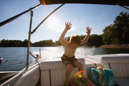 Young boy getting splashed from behind on a boat.