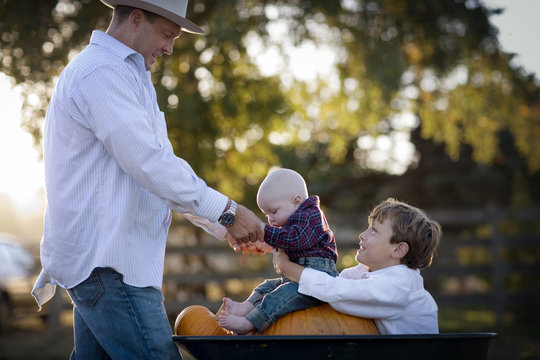 Happy father and his two young sons at a pumpkin patch.
