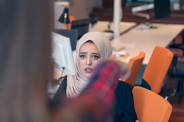 Worried arabic businesswoman wearing hijab receiving a notification from a colleague in her workplace at office - obrazy, fototapety, plakaty