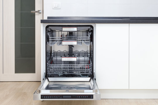 Build-in dishwasher with opened door in a white kitchen 
