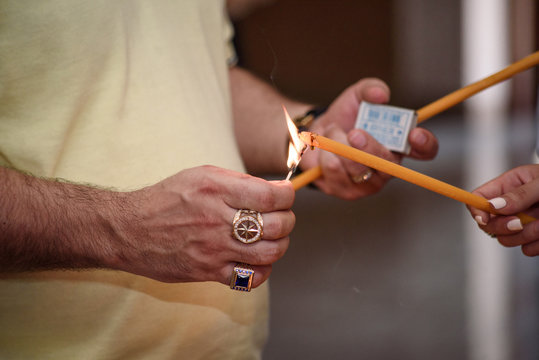man hand lighting candles in a church.