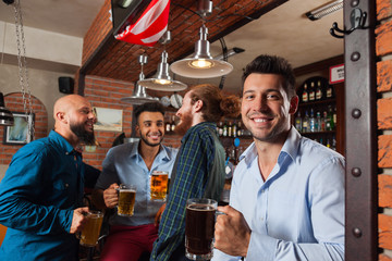 Man Group In Bar Hold Glasses Talking, Drinking Beer Mugs, Mix Race Cheerful Friends Wear Shirts