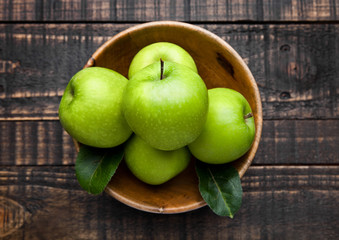 Green organic healthy apples in bowl on wooden board