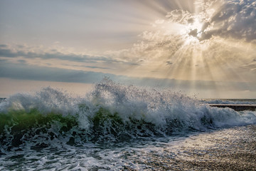 Wave breaking on the pebble shore at sunset