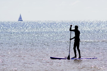 Silhouette of a person standing on a paddle board