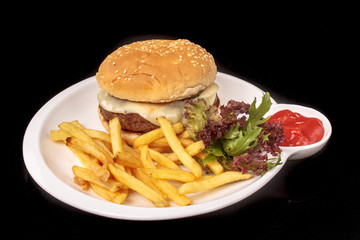 Cheeseburger with French fries, lettuce and ketchup lying on a s