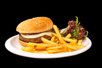 Cheeseburger with French fries, lettuce and ketchup lying on a s