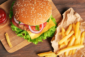 Tasty cheeseburger with fries on wooden table