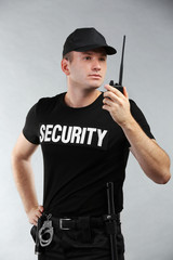 Fototapeta na wymiar Male security guard on grey background
