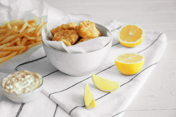 Tasty nuggets in plate and lemon on napkin