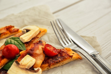Sliced tasty pizza on parchment, closeup