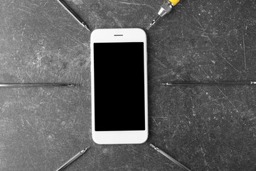Mobile phone, screwdriver and exchangeable bits on grey background
