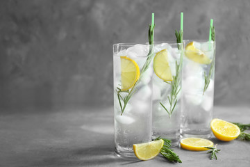 Glasses of cocktail with ice on grey background