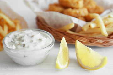 Bowl with sauce and lemon slices on table, closeup