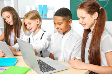 Schoolchildren sitting in classroom with laptop and tablet computer