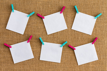 Six misaligned blank white notepads on hessian