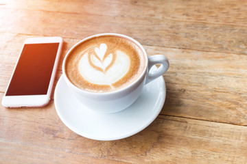 Coffee cup and mobile phone on wood table background, fillter ef