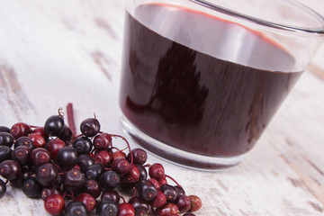 Bunch of fresh elderberry with juice on old wooden background, healthy nutrition