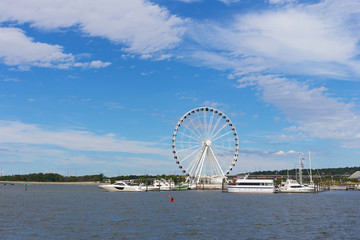 Ferris of National Harbor in Oxon Hill, Maryland, USA. Boats and yachts at National Harbor pier on a bright sunny day.