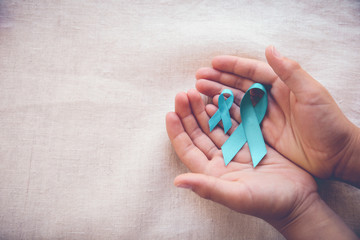 Hands holding Teal Ribbons, copy space toning background, Ovarian Cancer, cervical Cancer, Kidney Cancer awareness