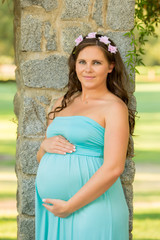 Young pregnant woman in a park holding her belly