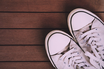 Old canvas shoes on a wooden floor Vintage Retro Filter.