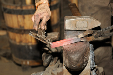 Blacksmith working in the forge processes the metal .