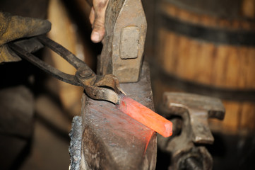 Blacksmith working in the forge processes the metal .