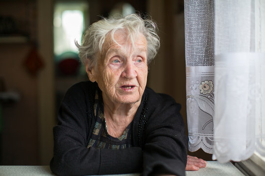 Elderly Woman Portrait At The Kitchen Table.