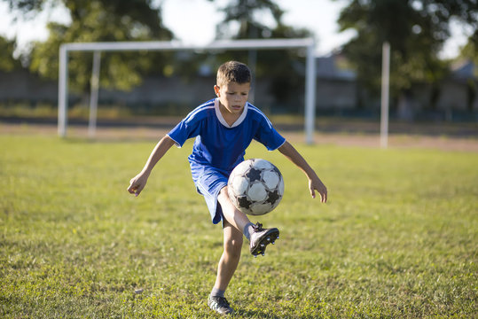 Boy kicking soccer ball on the football field